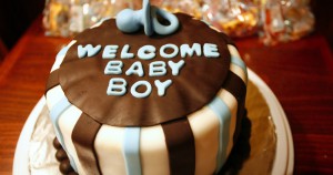 Stax Bakery cake that says welcome baby boy in blue on top of a layer of chocolate cake.