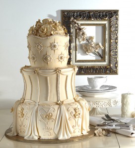 Stax Bakery Wedding Cake set up with cutlery a candle and a frame with a flower in it displayed around the decorative cake.