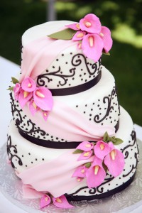 Stax Bakery Wedding cake with a pink flower and sash design going down the cake layers.
